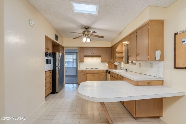 5301 E 4th St, Tucson, AZ 85711 - kitchen with a peninsula, freestanding refrigerator, light countertops, wall oven, and a sink