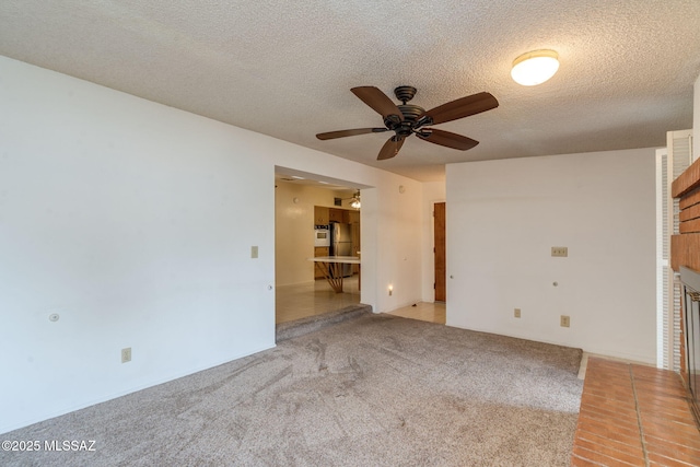 5301 E 4th St, Tucson, AZ 85711 - unfurnished living room with ceiling fan, carpet flooring, a fireplace, and a textured ceiling