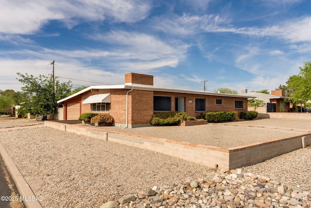 5301 E 4th St, Tucson, AZ 85711 - single story home featuring brick siding, a chimney, an attached garage, and driveway