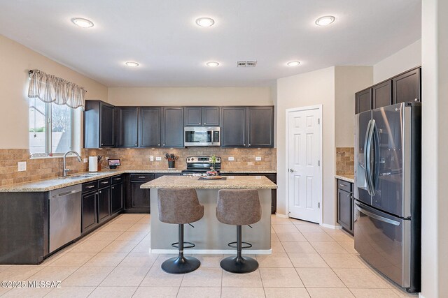 10487 S Cutting Horse Dr, Vail, AZ 85641 - kitchen with stainless steel appliances, a sink, a center island, light stone countertops, and tasteful backsplash