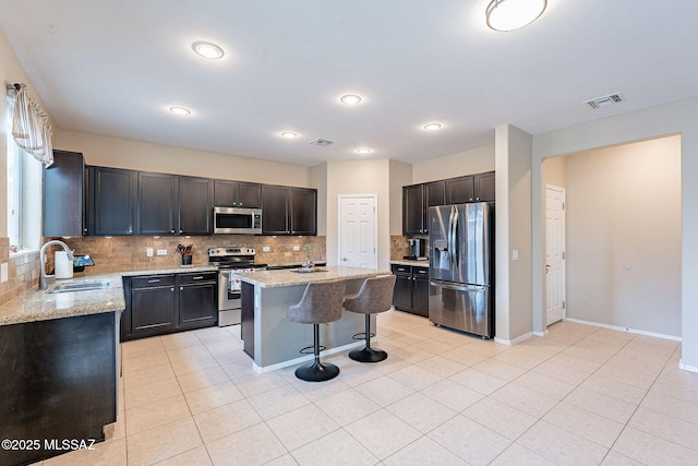 10487 S Cutting Horse Dr, Vail, AZ 85641 - kitchen featuring stainless steel appliances, a sink, a breakfast bar, decorative backsplash, and light stone counters