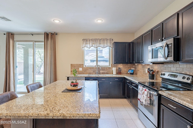 10487 S Cutting Horse Dr, Vail, AZ 85641 - kitchen with stainless steel appliances, a sink, tasteful backsplash, a center island, and light stone counters
