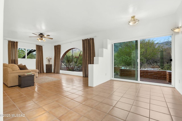 4921 E Camino De Los Olivos, Tucson, AZ 85718 - unfurnished living room with light tile patterned floors, a ceiling fan, and plenty of natural light