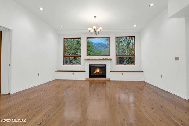 4921 E Camino De Los Olivos, Tucson, AZ 85718 - unfurnished living room with a chandelier, hardwood / wood-style floors, recessed lighting, a glass covered fireplace, and baseboards