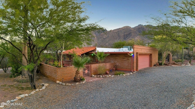 4921 E Camino De Los Olivos, Tucson, AZ 85718 - view of side of property with an attached garage, a mountain view, gravel driveway, and brick siding