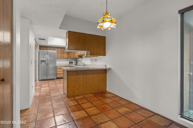 9350 E Speedway Blvd Unit 6, Tucson, AZ 85710 - kitchen with stainless steel refrigerator with ice dispenser, brown cabinetry, a peninsula, a textured ceiling, and light countertops