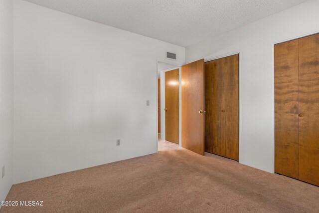 9350 E Speedway Blvd Unit 6, Tucson, AZ 85710 - unfurnished bedroom featuring carpet floors, multiple closets, and a textured ceiling