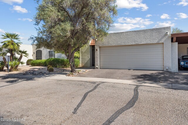 9350 E Speedway Blvd Unit 6, Tucson, AZ 85710 - view of front of house with stucco siding, a garage, and asphalt driveway