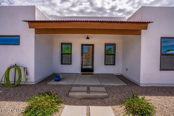 entrance to property with stucco siding and a patio