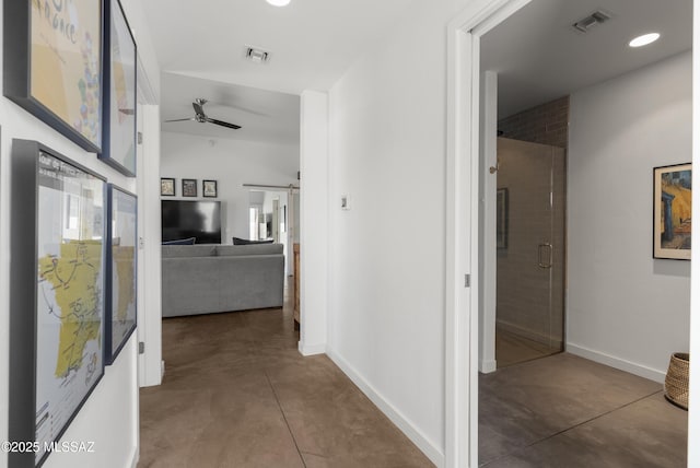 hall featuring finished concrete flooring, baseboards, and recessed lighting