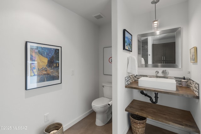 bathroom with baseboards, toilet, and a sink