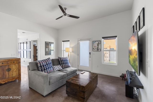 living room with concrete floors, ceiling fan, and baseboards