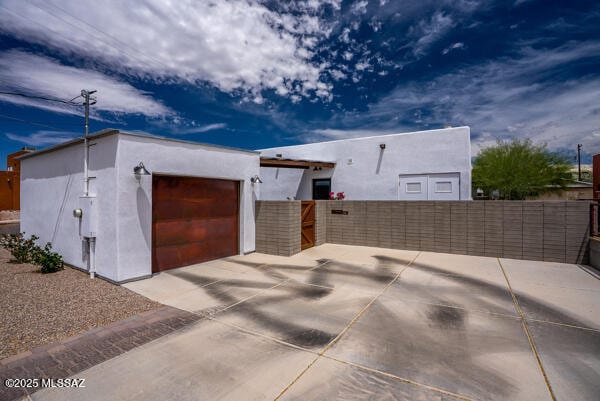 view of front of home featuring an attached garage, fence, stucco siding, and concrete driveway