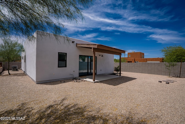 back of house with a patio area, a fenced backyard, stucco siding, and central AC unit