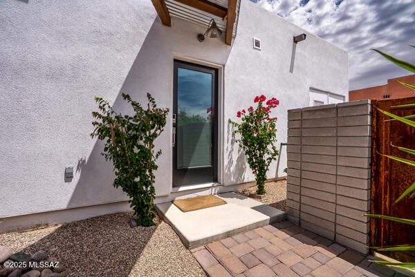 property entrance with fence and stucco siding