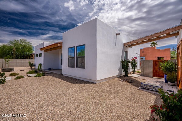 rear view of house featuring a fenced backyard, a patio area, and stucco siding