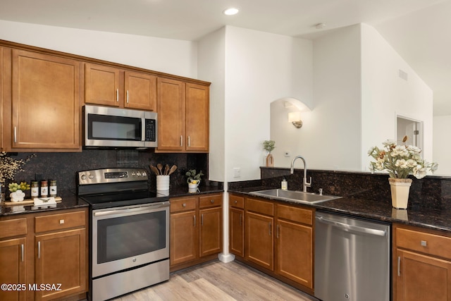 12356 N Globe Mallow Pl, Marana, AZ 85658 - kitchen with appliances with stainless steel finishes, brown cabinets, light wood-style flooring, tasteful backsplash, and dark stone counters