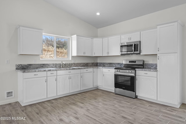 1895 Roma Ct, Rio Rico, AZ 85648 - kitchen with appliances with stainless steel finishes, white cabinetry, light wood finished floors, a sink, and vaulted ceiling
