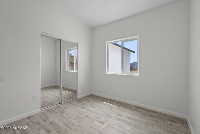 1895 Roma Ct, Rio Rico, AZ 85648 - unfurnished bedroom with multiple windows, baseboards, wood tiled floors, and a closet