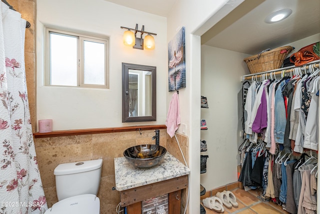 2120 N Fair Oaks Ave, Tucson, AZ 85712 - full bathroom featuring vanity, toilet, tile walls, a wainscoted wall, and a walk in closet