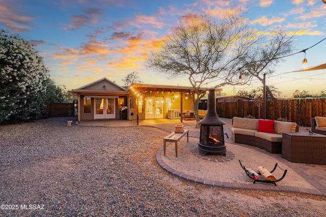 2120 N Fair Oaks Ave, Tucson, AZ 85712 - back of house at dusk featuring french doors, a patio, a fenced backyard, and an outdoor living space with a fire pit