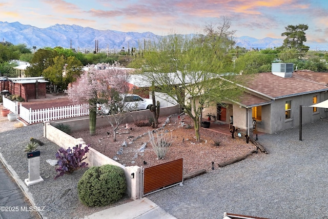2120 N Fair Oaks Ave, Tucson, AZ 85712 - view of front of property featuring a fenced front yard, a mountain view, stucco siding, a shingled roof, and central air condition unit