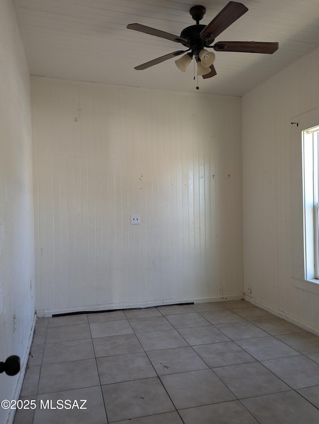 spare room featuring a ceiling fan, tile patterned flooring, wooden walls, and baseboards