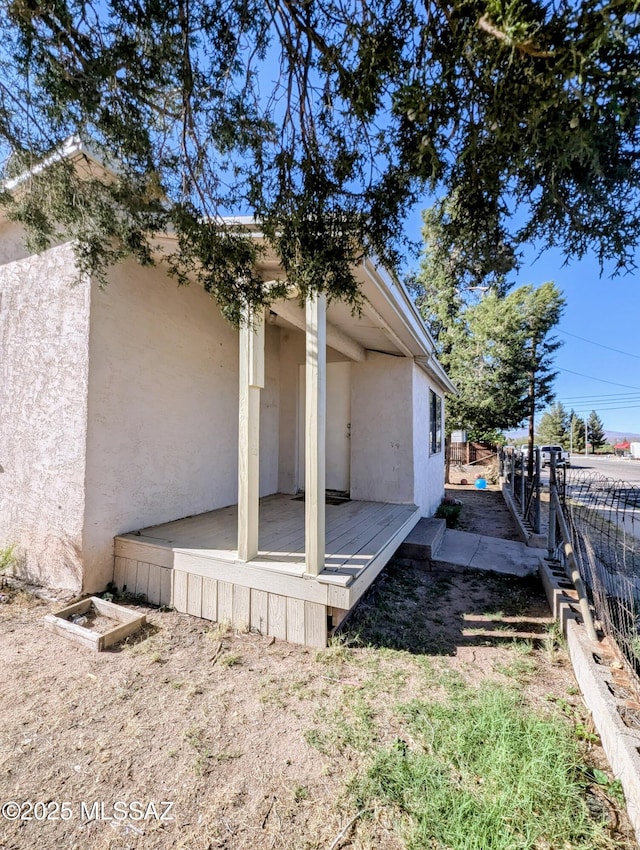 view of home's exterior with stucco siding and fence