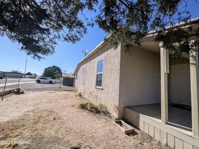view of side of home with stucco siding and fence