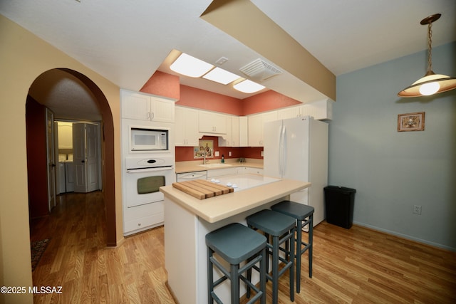 980 W Camino Sagasta, Green Valley, AZ 85622 - kitchen with white appliances, light wood-style flooring, light countertops, white cabinetry, and a breakfast bar