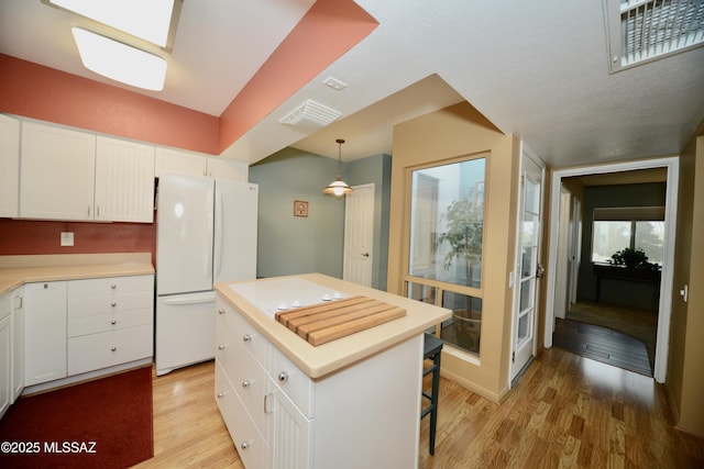 980 W Camino Sagasta, Green Valley, AZ 85622 - kitchen with freestanding refrigerator, light wood-type flooring, white cabinets, light countertops, and a center island