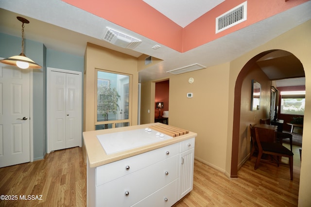 980 W Camino Sagasta, Green Valley, AZ 85622 - kitchen with arched walkways, light wood-style floors, white cabinets, light countertops, and hanging light fixtures