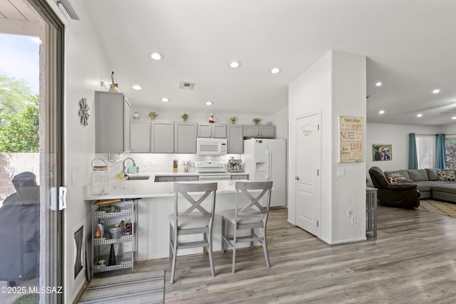 519 W Silvertip Rd, Tucson, AZ 85737 - kitchen featuring white appliances, gray cabinets, a peninsula, light wood-type flooring, and backsplash