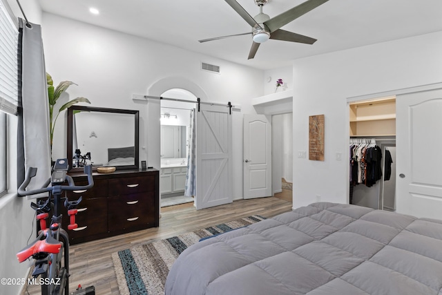 519 W Silvertip Rd, Tucson, AZ 85737 - bedroom with a barn door, light wood-style flooring, ensuite bathroom, a walk in closet, and recessed lighting