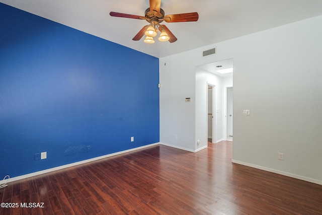 spare room featuring wood finished floors, a ceiling fan, and baseboards