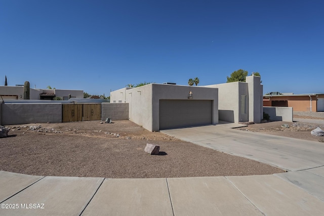 view of property exterior with stucco siding, concrete driveway, a gate, and a garage