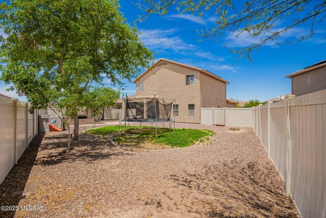 21185 E Reunion Rd, Red Rock, AZ 85145 - back of house with a trampoline, stucco siding, and a fenced backyard