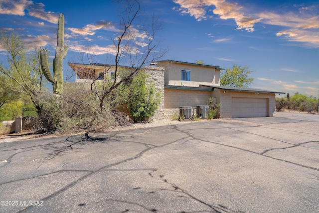 12220 E 5th St, Tucson, AZ 85748 - view of front of house featuring a garage, central AC unit, driveway, and stucco siding