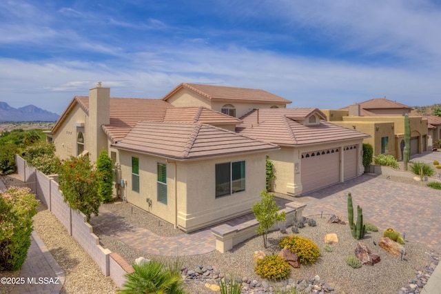 63063 E Mountain Crest Dr, Saddlebrooke, AZ 85739 - view of front of property featuring an attached garage, a tiled roof, stucco siding, decorative driveway, and a chimney