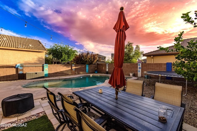 10676 S Miramar Canyon Pass, Vail, AZ 85641 - pool at dusk with outdoor dining space, a patio area, a fenced backyard, and a trampoline