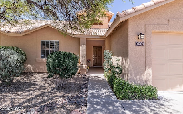 9664 E Paseo, San Rosendo, Tucson, AZ 85747 - view of exterior entry featuring a garage, stucco siding, and a tile roof