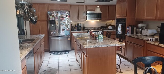 4081 N Hidden Cove Pl, Tucson, AZ 85749 - kitchen with stainless steel appliances, a kitchen island, light tile patterned floors, light stone counters, and decorative light fixtures