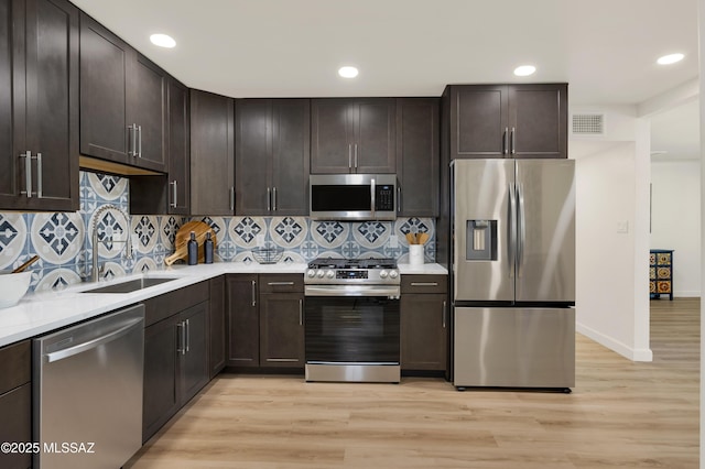 2610 E Elm St, Tucson, AZ 85716 - kitchen featuring appliances with stainless steel finishes, a sink, light countertops, light wood-style flooring, and dark brown cabinets