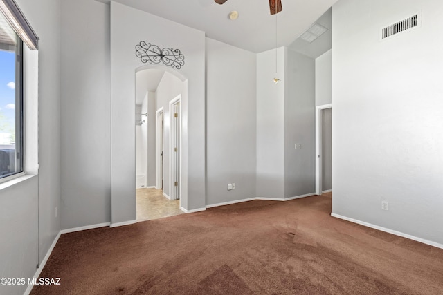 8807 S Desert Rainbow Dr, Tucson, AZ 85747 - spare room featuring carpet floors, arched walkways, ceiling fan, and baseboards