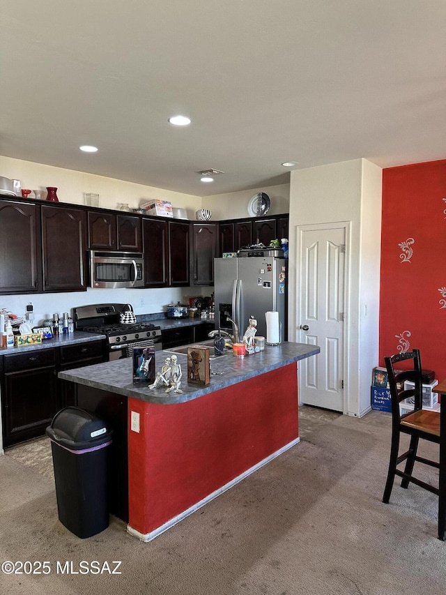 1027 E Madera Grove Ln, Sahuarita, AZ 85629 - kitchen featuring appliances with stainless steel finishes, dark countertops, a center island with sink, dark brown cabinets, and recessed lighting