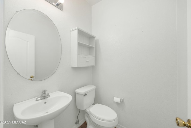 bathroom with a sink, toilet, and baseboards