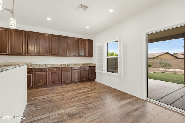 kitchen featuring light wood-type flooring, recessed lighting, baseboards, light stone countertops, and decorative light fixtures