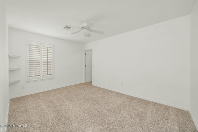 spare room with light colored carpet, a ceiling fan, and baseboards