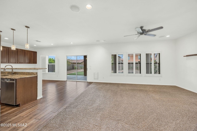 unfurnished living room featuring ceiling fan, recessed lighting, a sink, baseboards, and wood finished floors