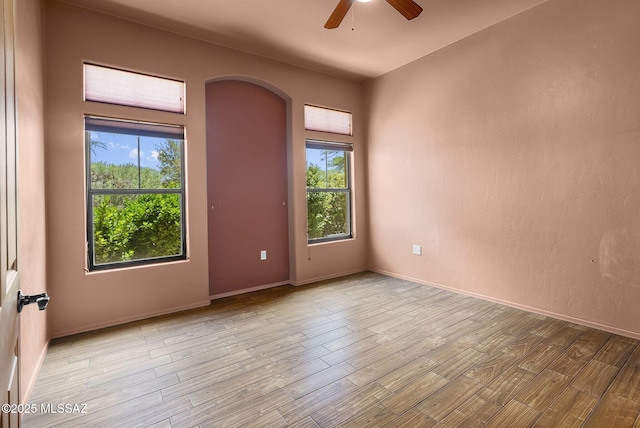 110 Post Way, Tubac, AZ 85646 - unfurnished room featuring arched walkways, ceiling fan, wood finished floors, and baseboards